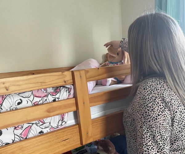 woman placing a teddy on a bunk bed